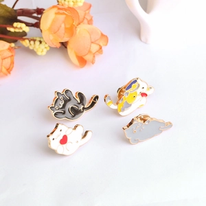 Detailed view of four colorful enamel cat pins in different playful poses on white surface