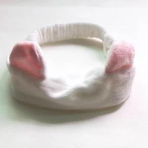 Close-up of soft white plush headband with cute pink cat ears for face washing