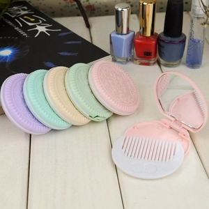 Detail of macaron-colored portable biscuit-shaped folding mirror and comb set