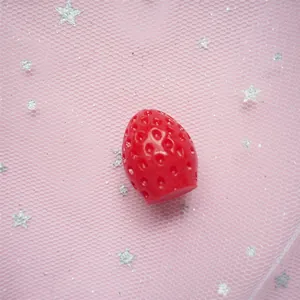 Close-up of red resin strawberry charms for DIY crafts and phone case decoration