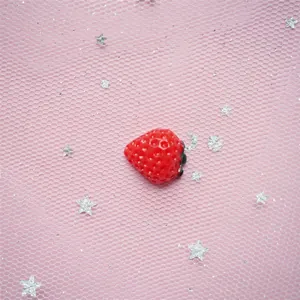Macro detail of red resin strawberry charms with realistic seeds for DIY crafts