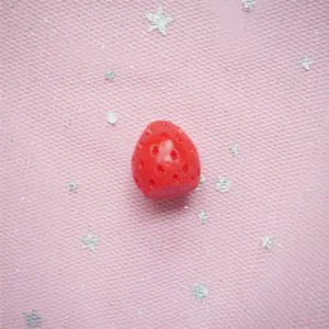 Detailed view of red resin strawberry charms with realistic texture for DIY crafts