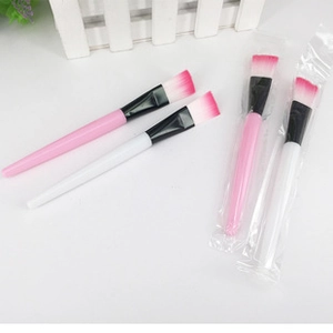 Flat macro view of four professional facial mask brushes with pink and white handles