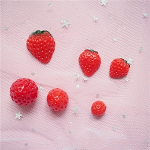Detailed view of DIY resin strawberry charms and textured beads on pink starry mesh