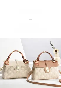 Quilted crossbody bag detail featuring gold rotating buckle and decorative silk scarf handle