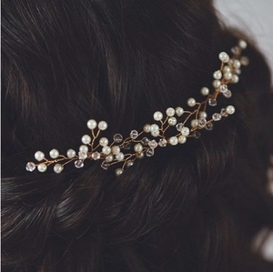 Detailed close-up of bridal hair piece with gold wire, white pearls, and clear crystals