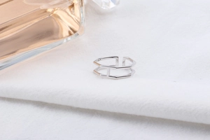 Macro shot of silver dual-layer geometric hollow ring on white linen with a soft focus