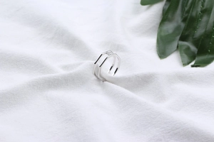 Detailed view of the S925 sterling silver hexagonal ring on white linen and leaves
