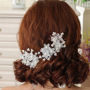 Detail of bridal hair pin with frosted white flowers, pearls, and crystals on a model