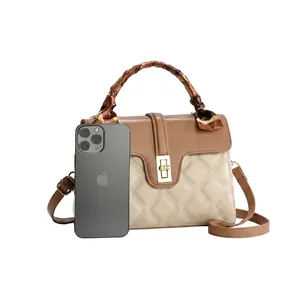 Detail view of beige and brown quilted handbag with gold twist lock and silk scarf