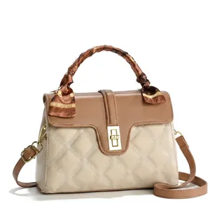 Detail of contrast stitch handbag with quilted pattern, gold metal lock and silk scarf