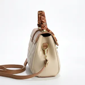 Detail of beige and brown crossbody bag with quilted texture and silk scarf handle