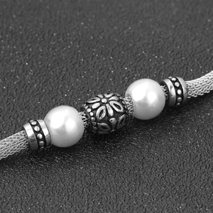 Vista macro del bracciale vintage in maglia d'acciaio con perle bianche e perle incise