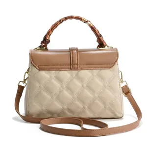 Detail of quilted leather handbag with scarf-wrapped handle and golden metal lock
