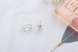 Macro view of silver S925 sterling silver H-shaped open ring on white fabric