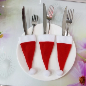 Three red and white Christmas hat cutlery holders displayed on a white plate