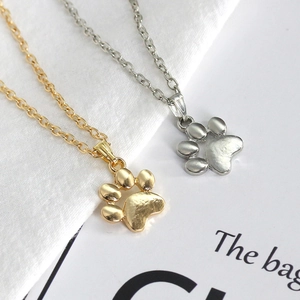 Detail showing polished gold and silver cat paw pendant necklaces on a clean background