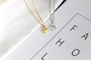 Detail of silver and gold cat paw necklaces on a card for a minimalist fashion look