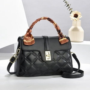 Elegant black quilted handbag with gold lock and silk scarf wrapped on top handle