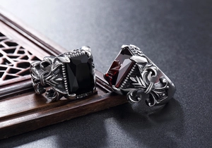 Detailed macro view of gothic punk rings with red and black stones on dark rock