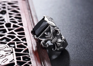 Macro detail of men's retro silver ring with rectangular black gem and fleur-de-lis