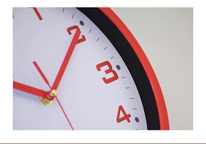 Macro shot of 10 inch wall clock showing red artistic numbers and polished hands