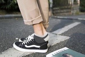 Dettaglio di calzini bassi in cotone con scarpe in tela nere e pantaloni color kaki