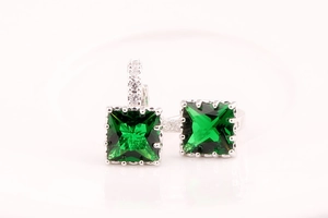 Primer plano de pendientes de plata con piedras verdes cuadradas y circonitas pavé