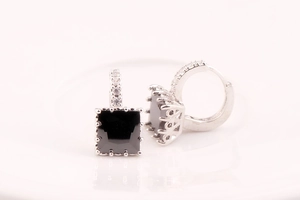 Macro view of square black gemstone hoop earrings with silver zircon pavé setting