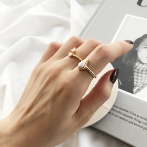 Detail of stacked gold S925 silver rings with triangular zircon and white inlay on hand