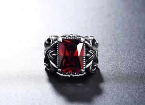 Macro shot of vintage gothic cross ring featuring a large emerald-cut red gemstone