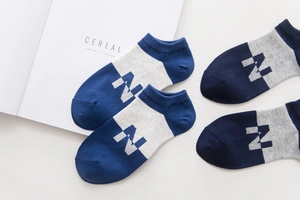 Dettaglio di fantasmini in cotone blu e grigio con lettera N su trama bianca