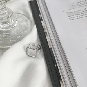 Detailed view of silver square micro-pave ring on elegant white silk fabric background