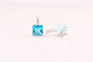 Detalle de pendientes de aro con circonita azul cuadrada y acabado en plata brillante
