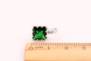 Close-up of square emerald green zircon earrings with ruler for size reference