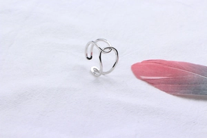 Detail of S925 sterling silver double-line crossover ring on a white textured background