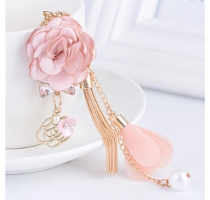 Dettaglio del portachiavi a fiore in tessuto rosa con nappe metalliche e perle