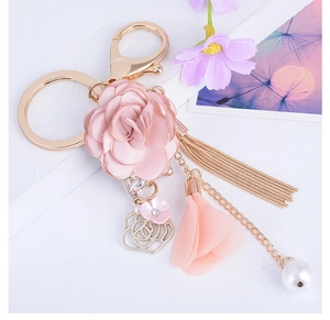 Dettaglio portachiavi rosa in tessuto con nappa rosa, frange metalliche e perla bianca