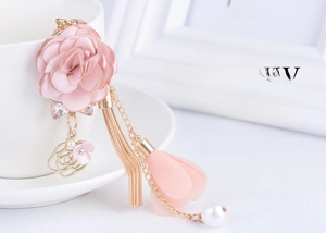 Dettaglio ciondolo fiore in tessuto rosa con nappe dorate e logo in stile Chanel