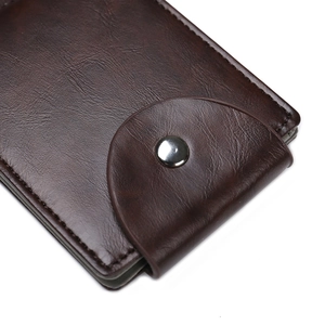 Macro shot of dark brown PU leather wallet with metallic snap button and lychee texture