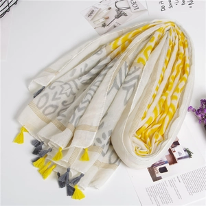 Detailed view of the yellow and grey tassel fringe on light cotton linen scarf
