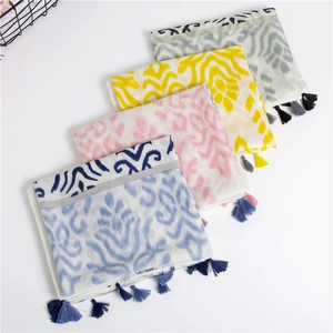 Detail of four colorful bohemian wavy print scarves with fringe on a white background