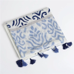 Detail of blue wave print pattern on white linen scarf with dark blue tassel fringe