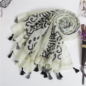 Detail of cream scarf with black abstract print and delicate tassel fringes on the edges