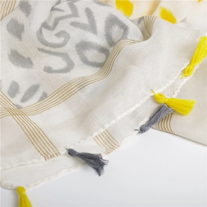 Detail of soft wave print cotton linen scarf featuring yellow tassels and light textures