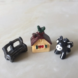 Macro shot of miniature resin black bench, cottage house and small animal figurines