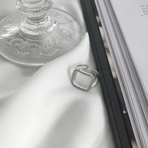 Macro shot of silver square ring with micro-pave zircons on white silk fabric