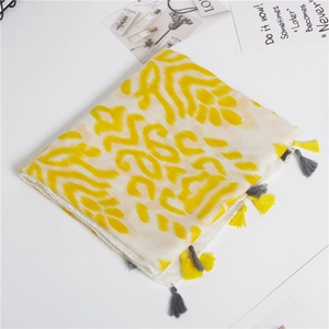 Detail of cotton linen scarf with yellow ikat patterns and fringed tassels on white