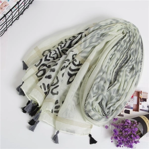 Detail of bohemian ivory shawl scarf featuring abstract leopard print and tassels