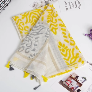 Detail of yellow and gray wavy print scarf with tassel edges on a white background